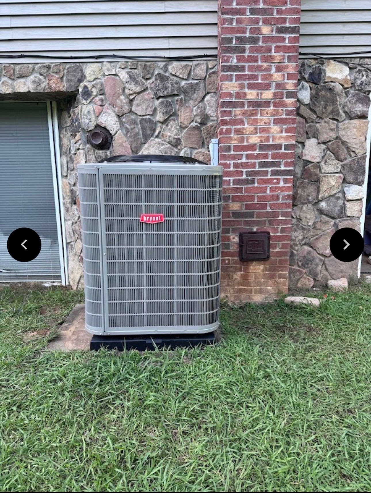 Bryant HVAC unit next to a brick chimney and stone wall