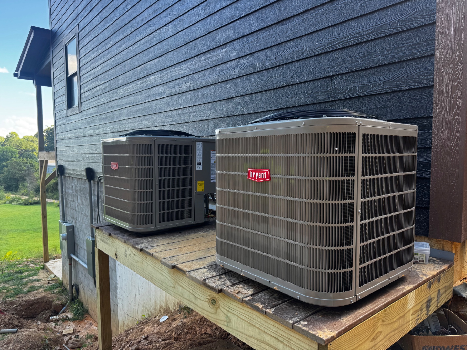 Two Bryant outdoor HVAC units installed on a raised platform