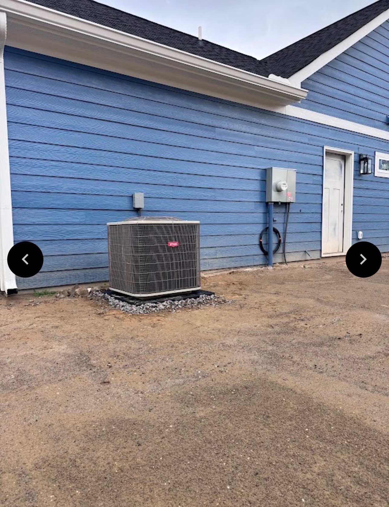 Bryant HVAC unit installed against a blue-sided house