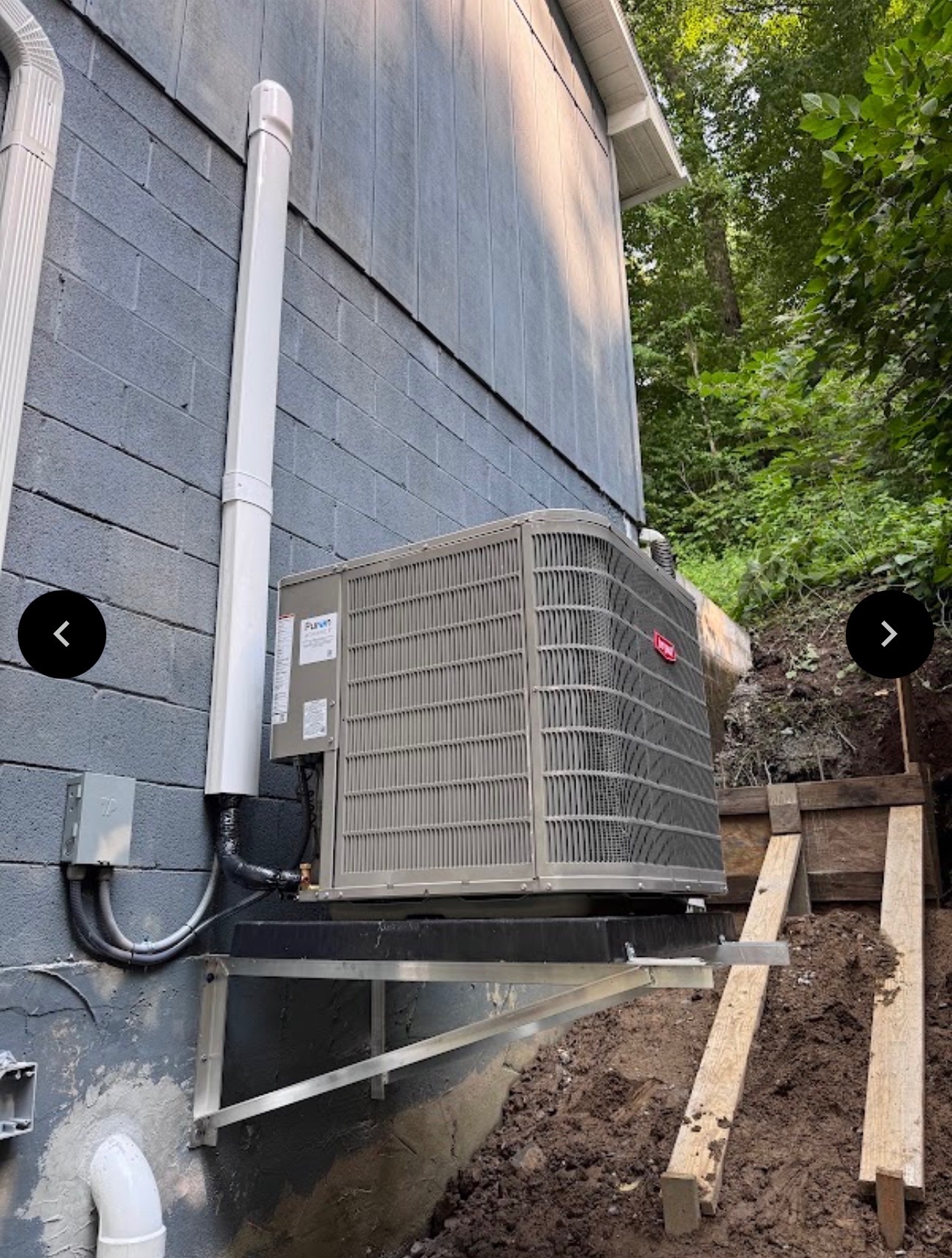 Bryant HVAC unit mounted on a wall bracket against a cinder block wall