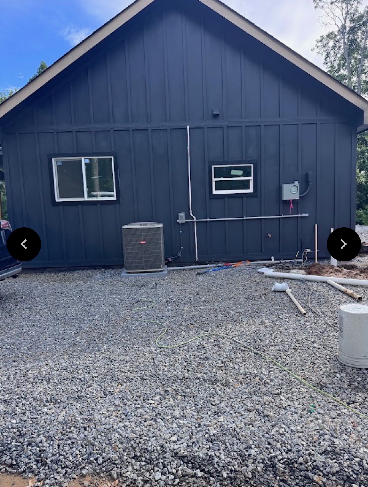 Bryant HVAC unit behind a dark-sided house on a gravel lot